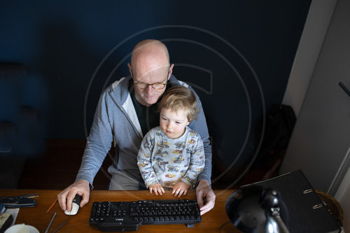 Mann mit Kleinkind am Schreibtisch