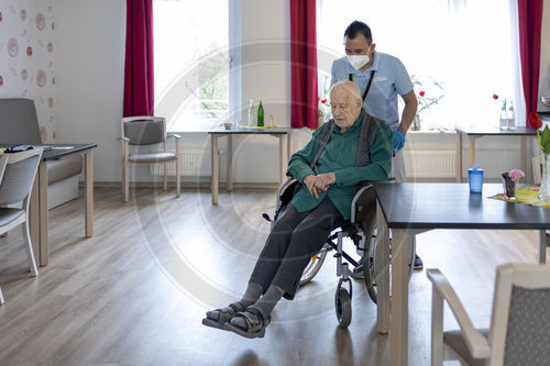 Altenpfleger schiebt einen Rollstuhl im Pflegeheim