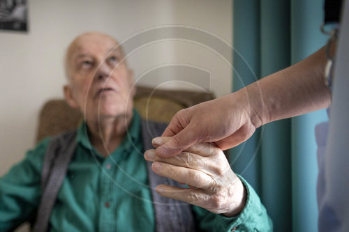Altenpfleger haelt die Hand eines alten Mannes im Pflegeheim
