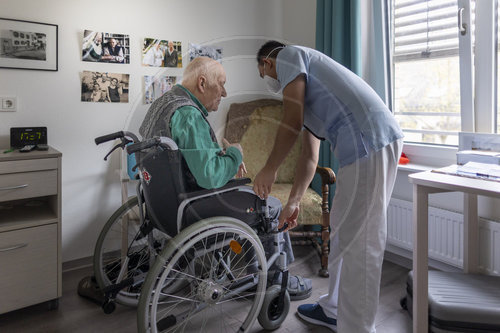 Alter Mann wird in einen Rollstuhl geholfen