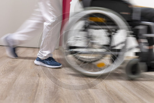 Altenpfleger schiebt einen Rollstuhl im Pflegeheim