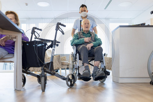 Pfleger mit Mann im Rollstuhl im Pflegeheim
