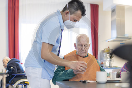 Pfleger hilft einem Mann zu trinken im Pflegeheim