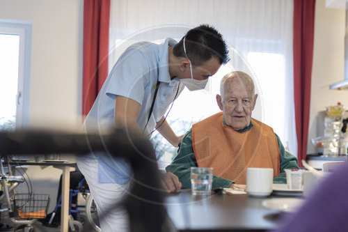 Pfleger spricht mit einem Mann im Pflegeheim