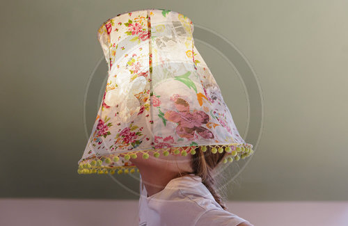 Maedchen mit einem Lampenschirm auf dem Kopf