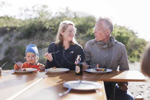 Sommerfest. Drei Generationen essen gemeinsam an einem Tisch.
