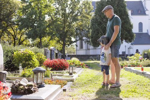 Mann mit Kind auf einem Friedhof