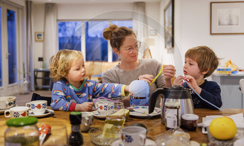 Mutter spielt mit ihren Kindern am Esstisch