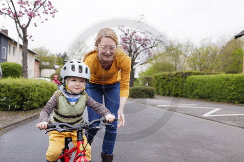 Kind mit Fahrrad/Laufrad auf der Strasse