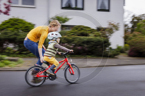 Kind mit Fahrrad/Laufrad auf der Strasse