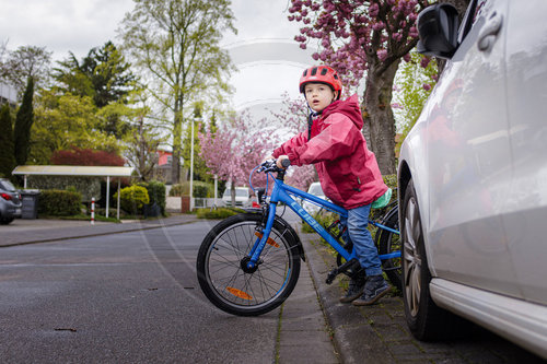 Kind mit Fahrrad/Laufrad auf der Strasse