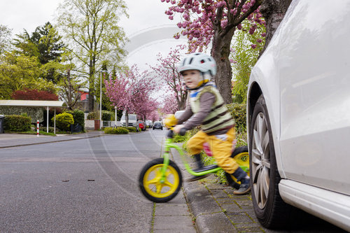 Kind mit Fahrrad/Laufrad auf der Strasse