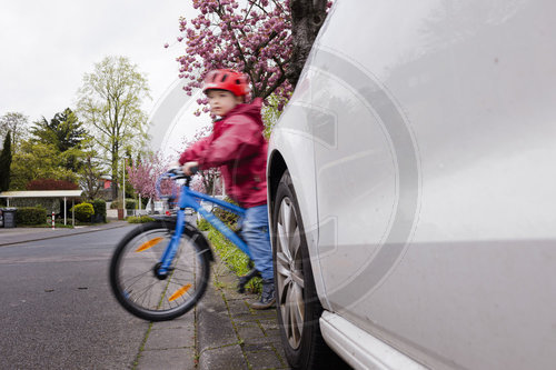 Kind mit Fahrrad/Laufrad auf der Strasse