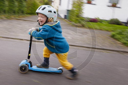 Kind mit Roller auf der Strasse