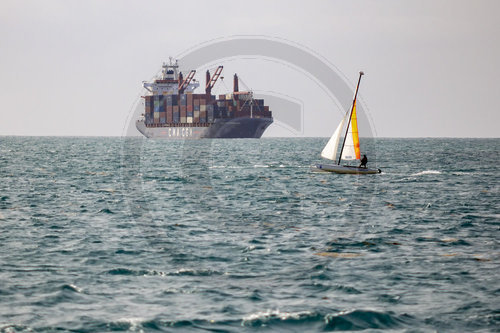 Ein kleines Segelschiff vor einen Containerfrachter