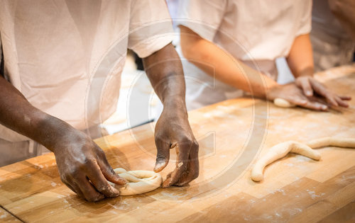 Baecker und Baeckerin formen Bretzel